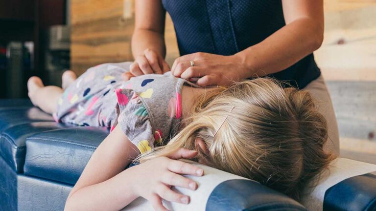 Person seated in a car using a cold pack on the neck while reviewing accident symptoms with a clinician.